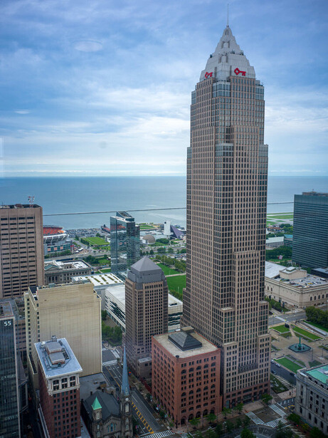 Tall art deco skyscraper with distinctive crown rising above surrounding buildings along a waterfront.
