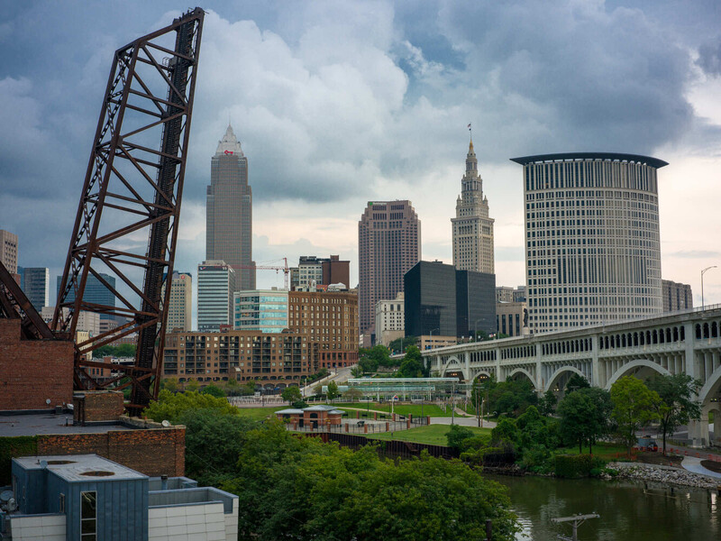 Cleveland skyline with vintage lift bridge, river, and downtown architecture under dramatic cloudy sky.