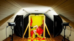 Professional studio setup with softboxes and key light illuminating red peppers on yellow background.